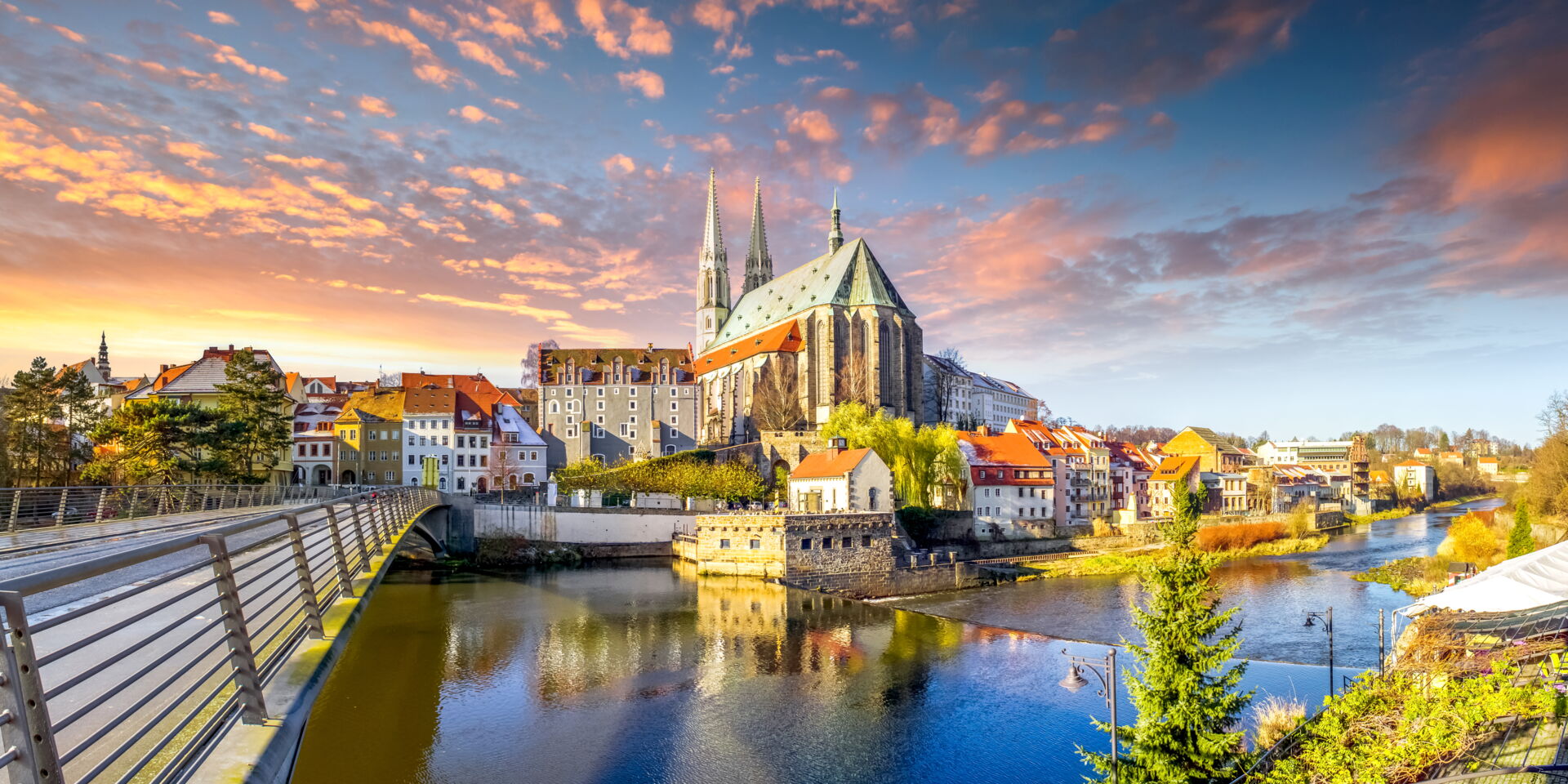 Panoramablick auf die Altstadt von Görlitz mit der Neiße und einer Brücke bei Sonnenuntergang mit dramatischen Wolken.