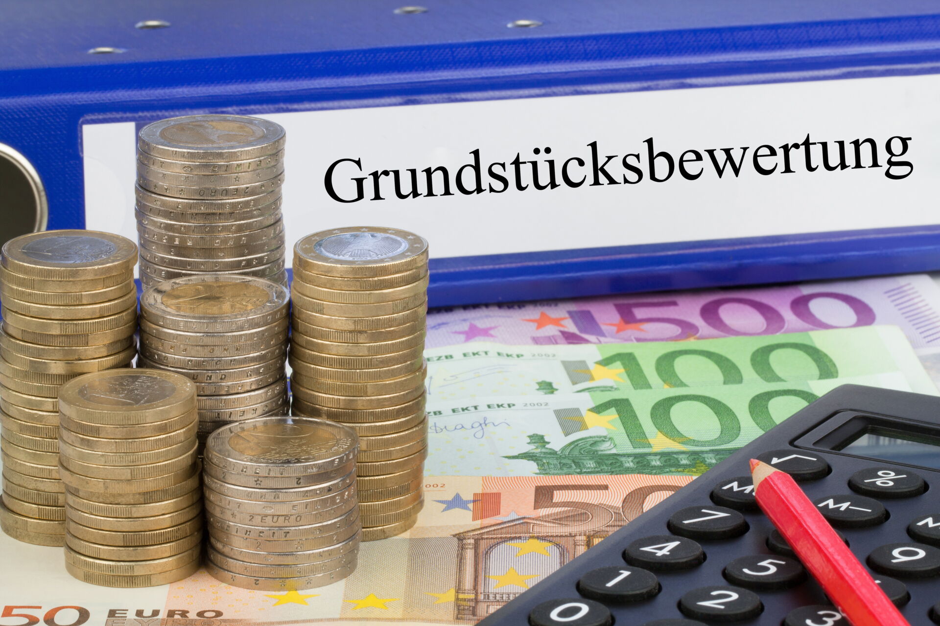 Ordner "Grundstücksbewertung", Euro-Münzen, Scheine, Taschenrechner und roter Stift deuten auf eine Immobilienbewertung in Dresden hin.